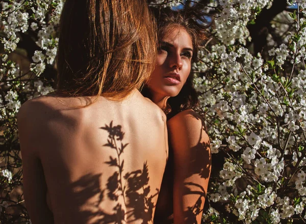 Belleza natural de primavera. Bloom pareja lesbiana en flor de cerezo parque. Hermosa chica sexy amigos con flores. — Foto de Stock