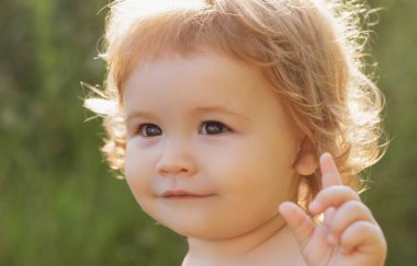 Güneşli bir günde yeşil doğa parkında şirin bir bebeğin portresi. Çocukluk ve ebeveynlik kavramı.