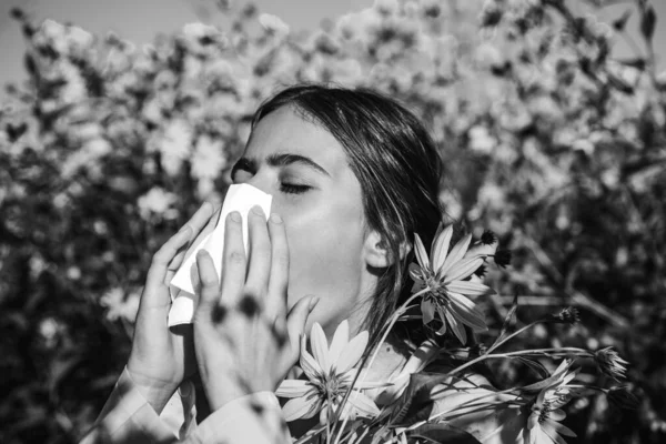 Young girl sneezing and holding paper tissue in one hand and flower bouquet in other. Young woman got nose allergy, flu sneezing nose. Young woman is going to sneeze. Flu. Closeup portrait. — Stock Photo, Image