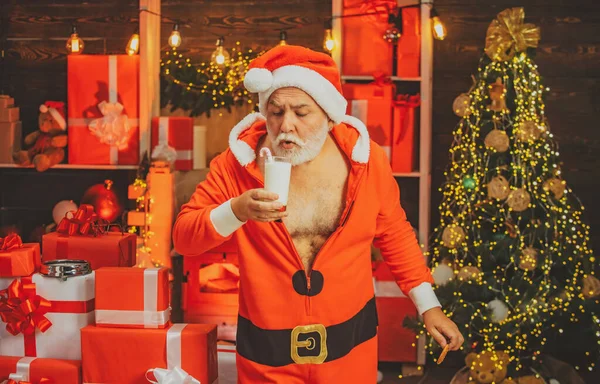 Papai Noel pegar biscoito e copo de leite em casa. Cartão de Natal. Biscoito de leite e gengibre para Papai Noel contra fundo de luz de Natal. — Fotografia de Stock