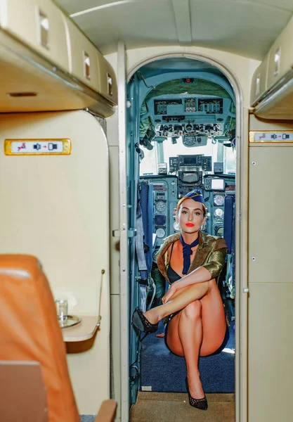 Ombord på ett kommersiellt flygplan. Flygvärdinna i blå uniform. Flygvärdinna klädd i uniform i flygplanets passagerarhytt. Ung kvinna i flygvärdinnekläder. Flygplan ombord. — Stockfoto