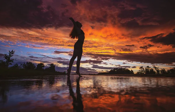 Zwart silhouet van mooi meisje of mooie vrouw, sexy slank model, met lang haar poseert op zee strand bij zonsondergang buiten op violette hemel achtergrond — Stockfoto