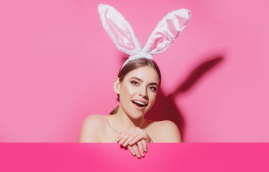 Tavşan kulaklı Paskalya tavşanı kadın. Pembe boş posterli güzel bir genç kız..