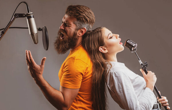 Couple singing. Friends with microphone singing song. Musician in music hall.