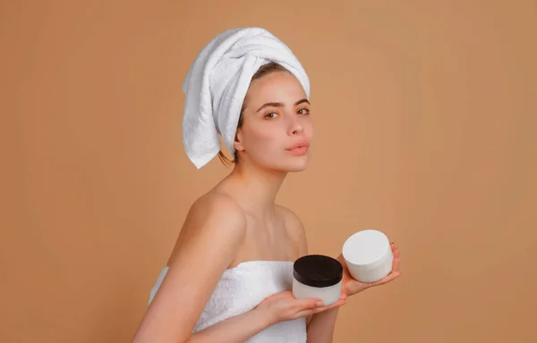 Face mask, spa beauty treatment, skincare. Woman with cream bottle. Beautiful young woman with clean perfect skin. Gestures for advertisement. Beige background — Stock Photo, Image
