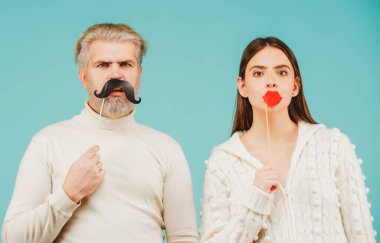 Parti malzemeleri. Sahte bıyıklı ve dudaklı mutlu çift eğleniyor. Fotoğraf kabini kavramı.