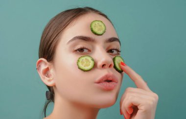 Yüz maskesi. Cilt bakımı. Yüzünde salatalık dilimleri olan genç bir kadın..