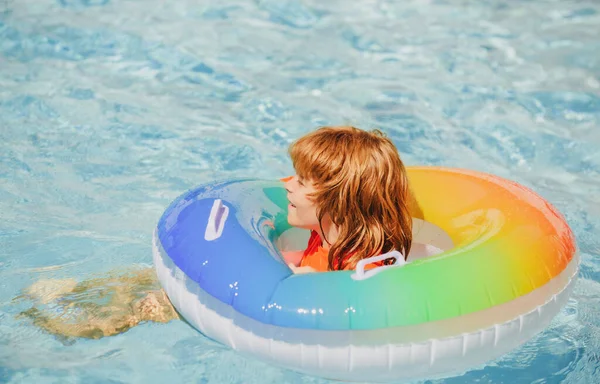 Zomervakantie. Een jongen in een zwembad. Kind in het aquapark. Grappige jongen op opblaasbare rubberen cirkel. — Stockfoto