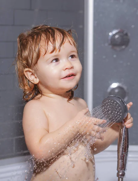 Gyerek fürdik a zuhany alatt. Fürdőruha. Boldog gyerek szappanhabbal a fején.. — Stock Fotó