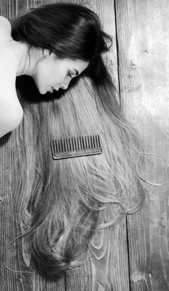 Шикарные волосы. Модель с вьющейся прической. Идея парикмахерской. Уход и средства для волос. Шампунь и кондиционер. Профессиональный. Потрясающая красота. Женщина с длинными волосами на деревянном фоне — стоковое фото