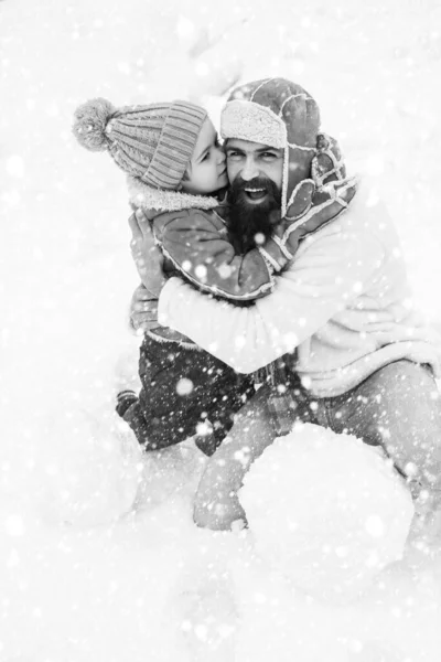 Família de Natal na neve. Papai e menino sorrindo e abraçando. Filho abraça seu pai em férias de inverno. Férias de Natal e inverno ano novo com pai e filho. Pai e filho brincando com neve no parque em — Fotografia de Stock