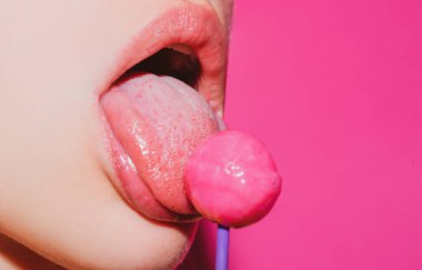 Dilini yalıyor. Ağız yalayan lolipop, kırmızı parlak dudaklar ve pembe renkli lolipop şekeri. Gece kulübü geçmişi.