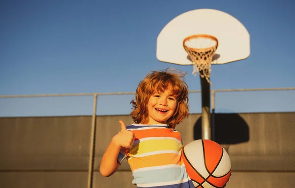 Sevimli gülümseyen çocuk basketbol oynuyor. Aktif çocuklar basket topuyla dışarıda oyun oynuyorlar. Sportif mutlu çocuk portresi gülüyor ve eğleniyor.. — Stok fotoğraf