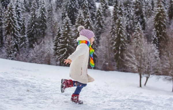 Funny excited child girl running in snow on winter outdoor. Children in winter outdoor in frost snowy day. — Stock Photo, Image