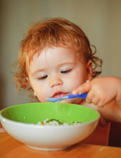Engraçado bebê na cozinha comendo com os dedos de prato. — Fotografia de Stock