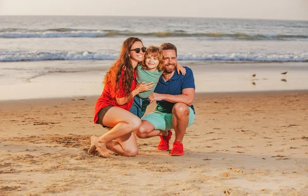 Glückliche Familie und Kind genießen den Sonnenuntergang am Strand. Sommerfreizeit. — Stockfoto