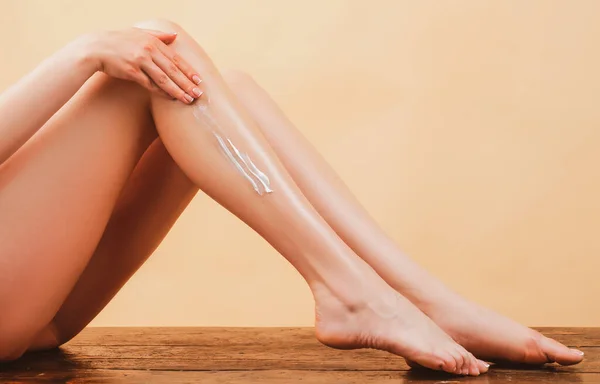 Оголена нога жінки. Жіночі руки наносять крем на шкіру, крупним планом. Косметичний крем на жіночій нозі з чистою м'якою шкірою. Наноситься зволожуючий крем на ноги. Целюліт або антицелюлітне лікування . — стокове фото