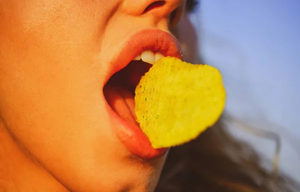 Mulut wanita makan keripik kentang. Chips dengan gigi, lidah dan bibir menutup. Makanan cepat saji yang lezat. Makan keripik. Makanan cepat saji. — Stok Foto