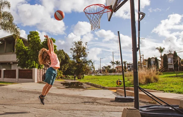 Söt liten pojke barn hoppar med korg boll för skott. Sport för barn utanför. Basket barn skolan. — Stockfoto