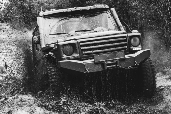 Mud and water splash in off-road racing. Offroad vehicle coming out of a mud hole hazard. Drag racing car burns rubber. Extreme. Off-road car. Rally racing.