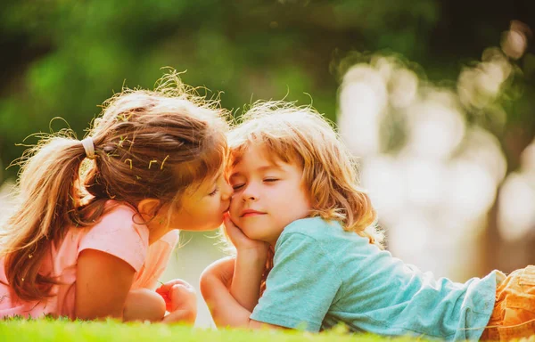 Słodka miłość. Dziewczynka całuje chłopaka na zewnątrz w parku. Relacje z dziećmi. — Zdjęcie stockowe