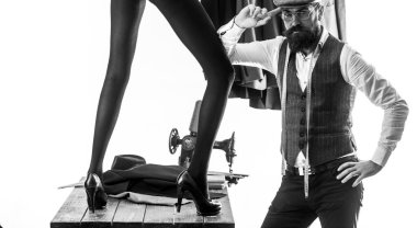 model ile sakallı adam tasarımcı. Romantik ve aşk. Detayların üzerinden geçiyor. erkek tarafından tasarlanan kadın moda. moda çift. Vogue. Fikirleri giyime dönüştürmek. Kendine güvenen bir terzi. Yetenekli terzi