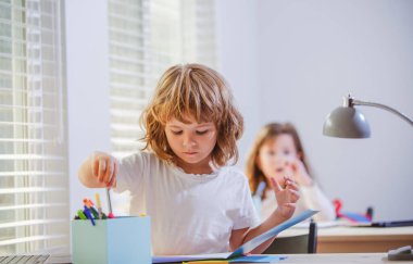 Birinci sınıf. Okula dönelim. Mutlu şirin çocuk içeride bir masada oturuyor. Cild derste öğreniyor..