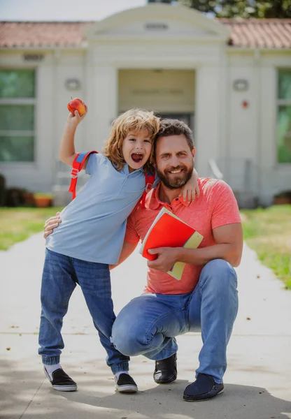 Père soutient et motive son fils. Le gamin va à l'école primaire. Bonne famille à la cour de l'école. — Photo