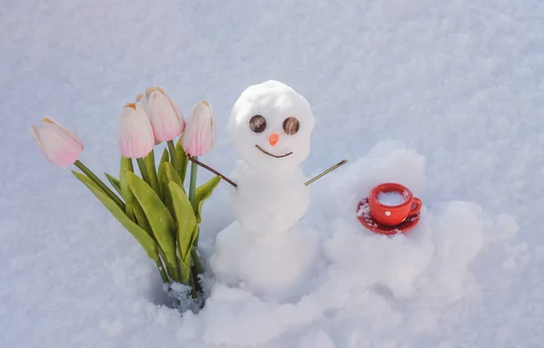 Winterweer. Lente sneeuwpop met koffiekop en bloemen. — Stockfoto