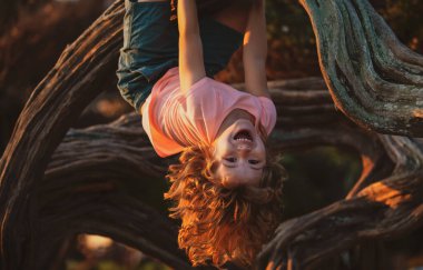 Küçük çocuk bir ağaca tepetaklak tırmanmaya çalışıyor..