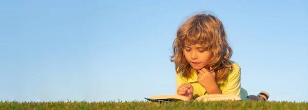 Banner with spring kids portrait. Kids imagination, innovation and inspiration children. Outdoor portrait of little boy reading a book. — стоковое фото