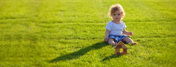 Banner con cara de niño primaveral. Niños de seguros. Bebé jugar en hierba verde. Tibia primavera en el parque. —  Fotos de Stock