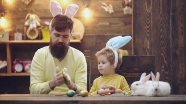 Happy family of father child son painted Easter eggs, wearing bunny ears on Easter day. Spring family holidays, kid boy and dad.