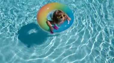 Havuzdaki çocuk, rahatla şişme yüzükte yüz ve yaz tatilinde suda eğlen..