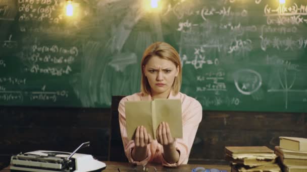 女子大学教授は授業の準備をしている。黒板の前の教室の机に座っている大学生。動揺、負の感情、悪い悲しい不幸な顔. — ストック動画
