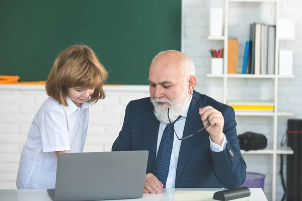 Pupil learning. Boy elementary school. Old and Young. Professor and pupil in classroom. Child at school lesson with senior teacher. — Φωτογραφία Αρχείου