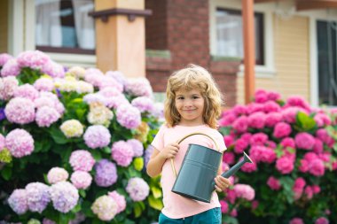 Kid boy in his flower garden. Portrait of a boy working in the garden in holiday.