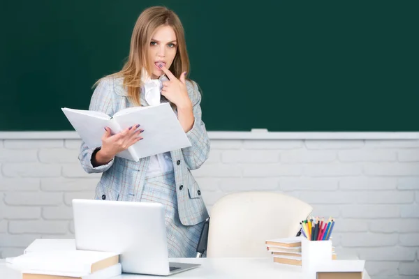 Female college student reading book in classroom, preparing for exam. — Stock fotografie