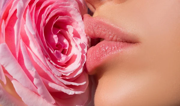 Woman kissing red rose flower. Lips with lipstick closeup. Beautiful woman lips with rose. — Stock Fotó