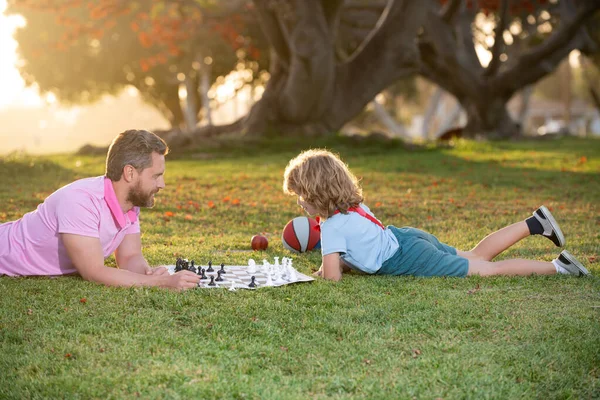 Father and son playing chess spending time together outdoor. Games and entertainment for children. Family concept. — Stock fotografie