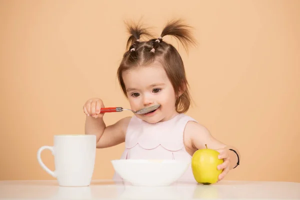 Baby child eating food. Kid eating healthy food with a spoon at studio, isolated. Funny kids face. — Stockfoto