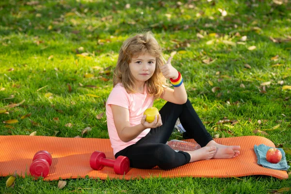 Sport kids boy. Healthy lifestyle and healthy food concept. Little boy child in sportswear eating apple sitting on sport mat after training on sunny spring day. — 图库照片