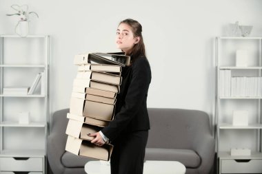 Sad businesswoman with many folders. Young businesslady at workplace in the office. Secretary woman in formal wear working on project at office.