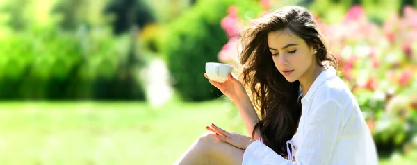 Spring time. Woman in summer field with coffee. Happy girl outdoors in rose garden. Woman enjoy outdoor recreation. Natural beauty. Spring design for banner or website header, copy space. — Stock Photo, Image