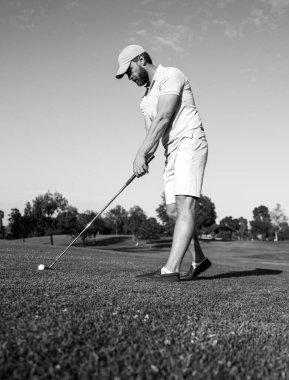 Golfçü akşam golf sahasında golf oynuyor. Güneşin altında golf oynayan bir adam..