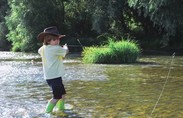 Kleine visser klaar om te gaan vissen. Jonge man vliegvissen. Schattige kleine jongen vissen op de vijver. Kid leren hoe te vissen houden van een staaf op een rivier. — Stockfoto