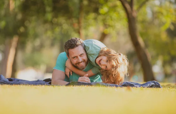 Schöner Vater huckepack Sohn spielt auf der Natur, Papa hält Reiten auf dem Rücken entzückende fröhliche Kind Junge genießen aktives Spiel. Kind umarmt und umarmt Eltern. — Stockfoto