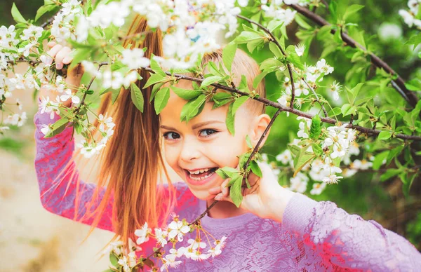 Portrét roztomilé teenager dívka při pohledu na kameru obklopen kvetoucí bílé třešňové větve v zahradě. — Stock fotografie