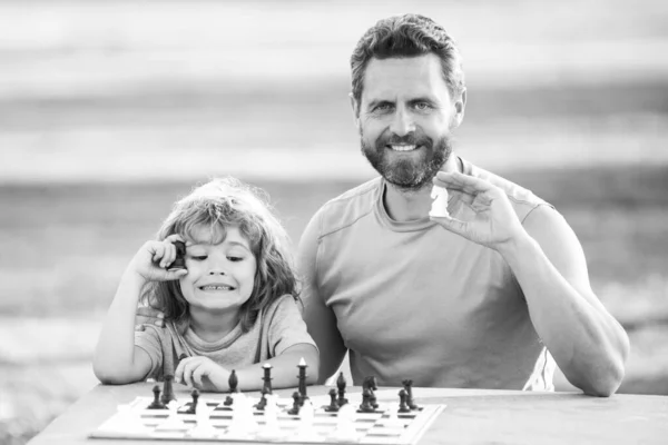 Отец играет с сыном в шахматы. Семья вне игры. Мальчик играет в шахматы. — стоковое фото