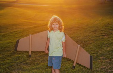 Gün batımında çim tarlasında sırt çantalı bir pilot. Pilot pilotçuluk oynayan ve parkta hayaller kuran bir çocuk..